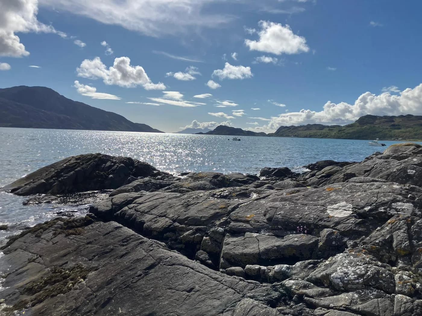 A rocky shoreline with mountains across the water