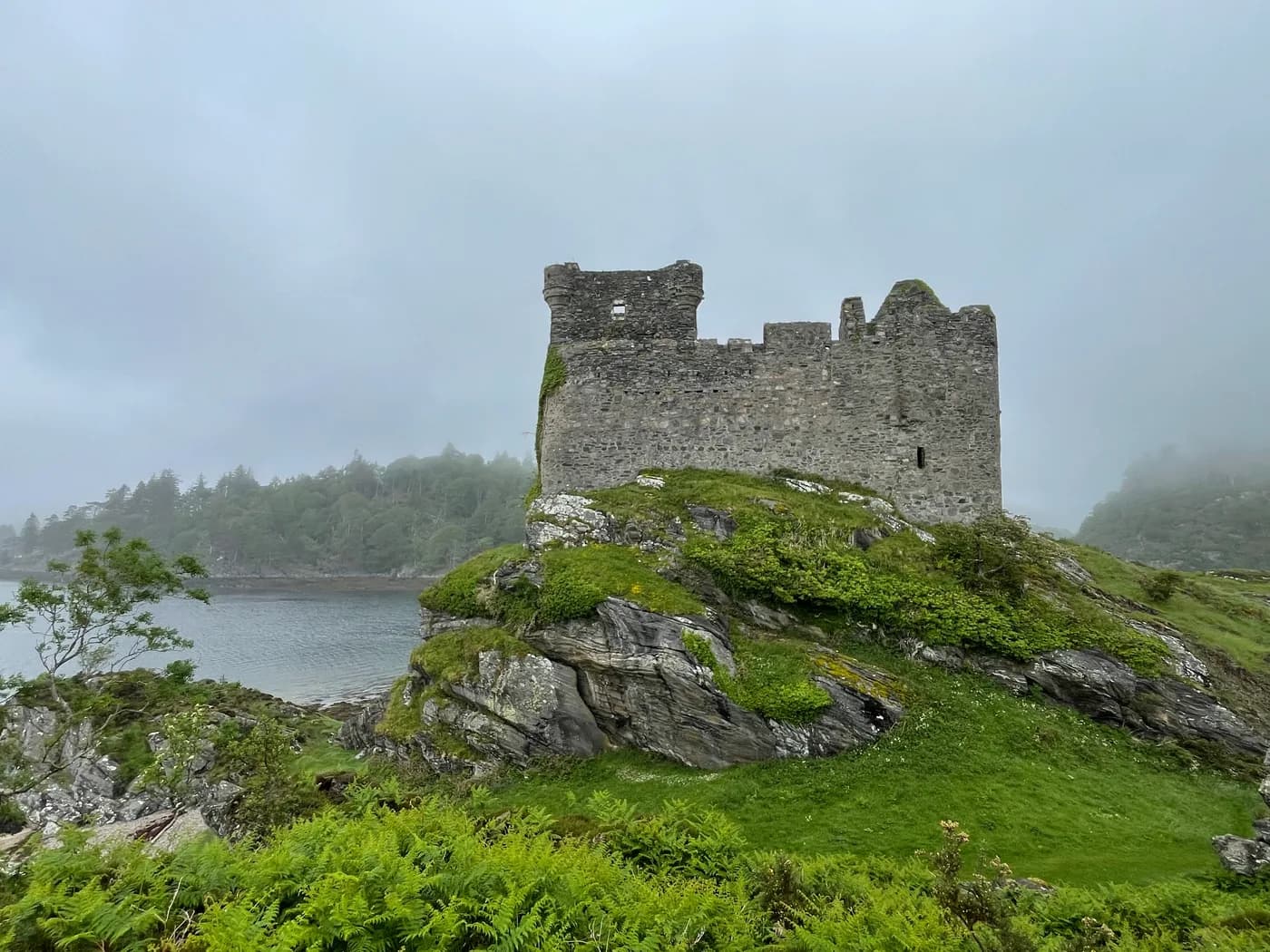 A ruined castle on a rocky outcrop beside the water