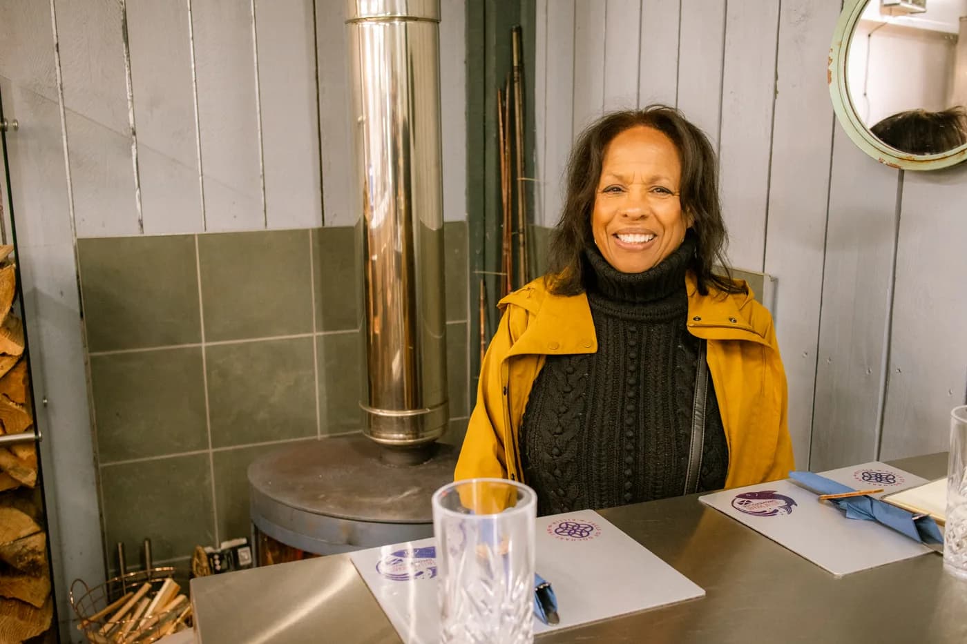 Allyson smiling at a café table beside a wood-burning stove