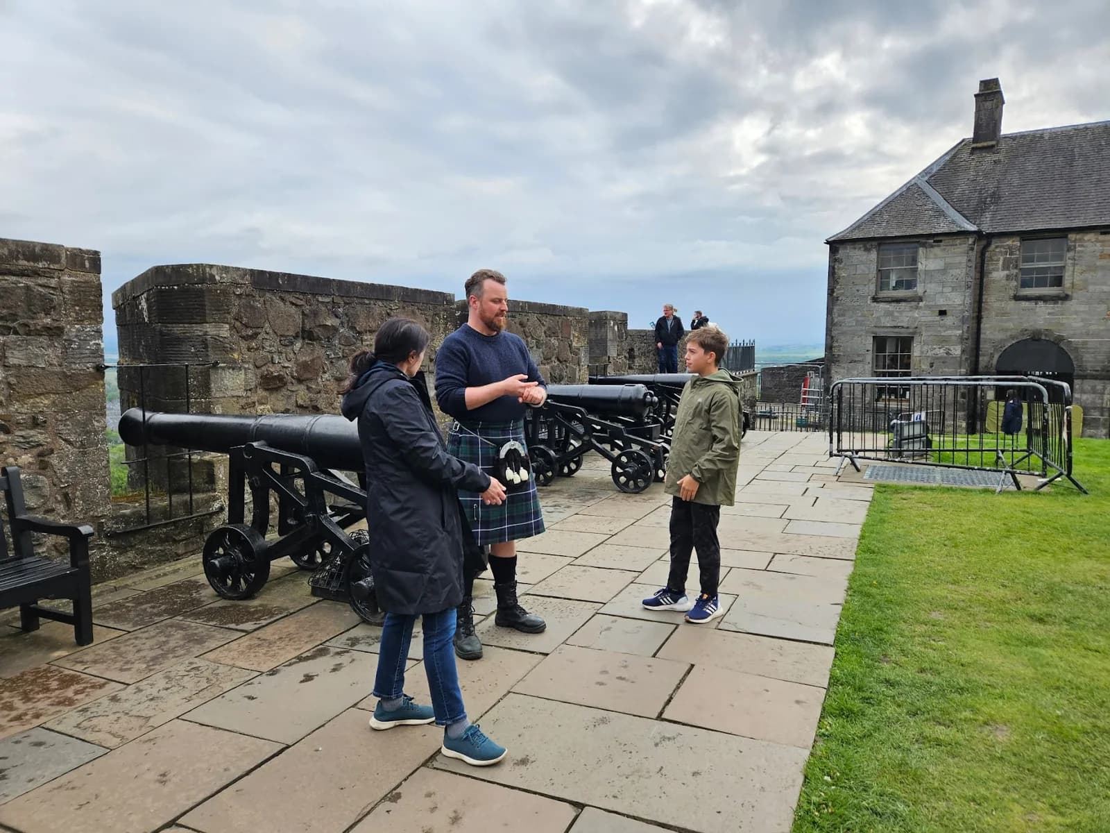 The family listening to a kilted guide beside historic cannons