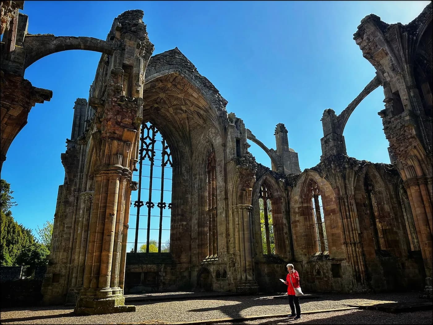 A guest exploring the sunlit ruins of Melrose Abbey